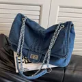 Blaue Denim-Kettentasche mit silbernem Drehverschluss und gesteppten Längsnähten - Blau