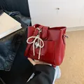 Minimalist burgundy bucket bag with glossy finish and pearl bow charm in luxury style - With Pendant / Red