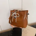 Brown bucket bag in glossy leather finish with pearl bow charm and shoulder strap - With Pendant / Brown