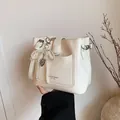 Sac seau chic en similicuir beige avec breloque nœud en perles et logo détaillé - Avec Pendentif / Blanc
