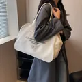 Grote crème canvas shopper met vintage letters gedragen over een grijze trenchcoat - Broken Wit