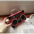 Detail of red vintage radio-shaped handbag with silver metal handle and buckle on a table - Red