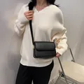 Elegante borsa a tracolla in pelle nera con fibbia dorata mostrata su modella - Nero