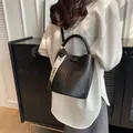 Elegant black lychee textured bucket bag for women with wide branded fabric shoulder strap - Black