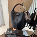 Schicke schwarze Bucket-Bag aus Leder mit Narbenstruktur und geometrischem Seidenschal - Schwarz