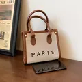 Bolso tote minimalista en lona color crema y cuero marrón con el texto Paris - Marrón Pequeño