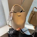 Elegante beige Bucket-Bag aus strukturiertem Leder mit dekorativem Seidenschal am Griff - Khaki