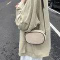 Chic beige oval crossbody bag with dark brown edges and suede texture worn outdoors - Off White