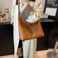 Detail of a brown woven leather hobo shoulder bag paired with a classic beige trench coat - Brown