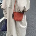 Caramel suede leather crossbody bag with heart pendant shown in a street style outfit - Red