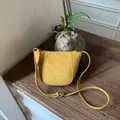 Handmade yellow suede leather crossbody bag with metal zipper on a wooden table - Amber Yellow