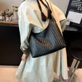 Classic black woven tote bag shown on model with a beige coat for daily fashion - Black