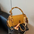 Caramel brown handbag with knot handle, metallic lock, and bohemian beaded charm - With Charm / Brown