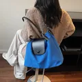 Large royal blue tote bag with black leather straps worn over a brown sweater - Blue