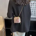 Vue de dos du modèle portant un mini sac en tweed rose avec une bandoulière dorée - Rose Petit
