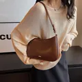 Dark brown leather underarm bag with gold metal logo and adjustable shoulder strap - Caramel color