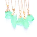 Nahaufnahme von fünf grünen Rohkristall-Anhängern mit vergoldeten Ketten auf weiß - Schatzgrün