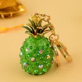 Mini-Ananas Schlüsselanhänger mit grünen Kristallen und goldenem Karabinerverschluss auf Gelb - Grün