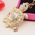 Sparkling turtle keychain with gold finish and rhinestones on a decorative background - 2.9x5.5cm / White
