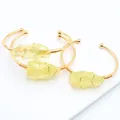 Detalle de piedra de citrino bruto envuelta en hilo en un brazalete abierto dorado - Citrina
