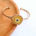 Detalle de una pulsera rígida de cristal de ágata girasol con borde bañado en oro - Amarillo