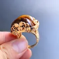 Detail of vintage gold-carved ring with embedded oval tiger eye stone and floral patterns - Tiger's Eye