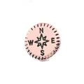 Vue macro d'un charm boussole en or rose avec rose des vents et gravure des directions - Style Boussole / Or rose