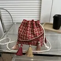 Detail of red tweed bucket bag featuring colorful tassels and woven drawstring straps - Red And White Plaid Tweed Style / Red