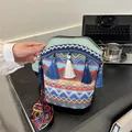 Close-up of bohemian woven bucket bag featuring colorful wave patterns and blue tassels - Green