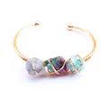 Detalle de cristales naturales envueltos en hilo de cobre en un brazalete dorado ajustable - Fluorita