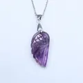 Detailed view of hand-carved purple amethyst angel wing pendant with silver metal chain - Purple Crystal