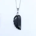 Détail macro du pendentif aile d'ange en agate noire sculptée sur une chaîne argentée - Obsidienne