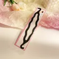 Detail of wavy black plastic hair styling tool in pink dotted packaging on a desk - Wave Style Braid Maker (Style 3)