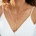 Collar dorado de varias capas con perlas y colgante de lazo en una modelo - Estilo de Múltiples Capas Perla Lazo Borla en Y Dorado (6621101HB)