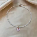 Elegant pearl choker necklace featuring a pink butterfly pendant with gold-tone metal trim - Pink Butterfly Pearl Choker Necklace