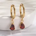 Détail de créoles dorées ornées de zircons rouges en forme de poire sur céramique blanche - Or / Rouge (E0080-1)