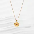 Macro shot of 18K gold flower pendant with red gemstone and sparkling stone bail - Flower Gold