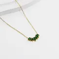 Macro detail of gold necklace with marquise-cut green gemstones in a fan-shaped pendant - Gold - Green Zirconia