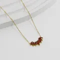 Makroaufnahme des fächerförmigen Anhängers mit roten Zirkonia und vergoldeter Kette - Gold-Roter Zirkonia