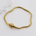 Macro detail of 18K gold-plated snake chain bracelet with textured spherical clasp - Gold Shell Clasp