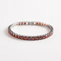Macro shot of silver tennis bracelet with square-cut red zircon stones and secure metal setting - Red