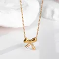 Nahaufnahme der goldenen Schleifen-Halskette mit funkelnden Kristallen auf weißem Steinhintergrund - Gold Schleife Stil (N0060)