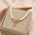 Detail of pearl necklace with gold OT buckle and diamond-encrusted letter E pendant - Gold E