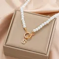 Macro view of a pearl necklace with a gold OT toggle clasp and crystal S letter pendant - Gold S