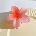 Detail of a 7cm pink gradient plumeria hair claw clip on a ceramic tray in natural light - Gradient Coral Orange Style (735006)
