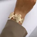 Elegantes goldenes Blumenarmband mit strukturierten Blüten am Handgelenk über Anzug - Goldenes Multi-Blumen Armreif (6464901)