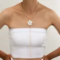 Elegante collar en forma de Y dorado con perlas blancas y colgante de flor en una modelo - 6510601hb