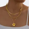 Primer plano de collar dorado de varias capas con cadena de serpiente y dije de flor - 6501801hb