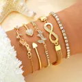 Primer plano detallado de un conjunto de cinco pulseras doradas con dijes de corazones - Cadena Tennis Oro Infinito Corazón Mariposa (6370701HB)