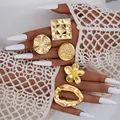 Set de 5 anillos dorados geométricos con motivos florales en la mano de la modelo - Juego Floral Cuadrado (6531501HB) / Set de 5 piezas / Dorado